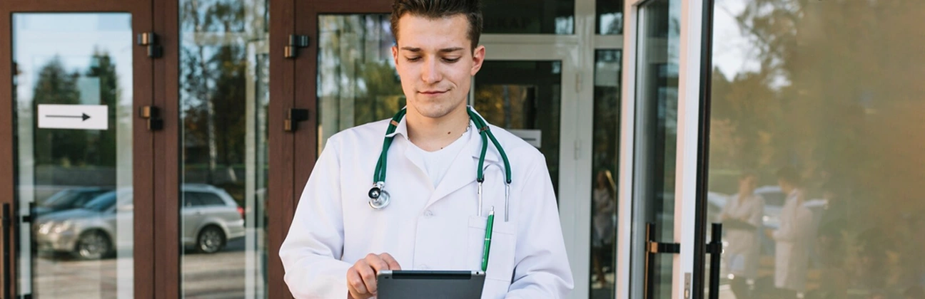 A doctor consulting a patient via telehealth on a laptop at home during the evening.